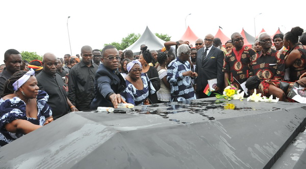 Kofi Sam pours perfume on the grave of his late father.