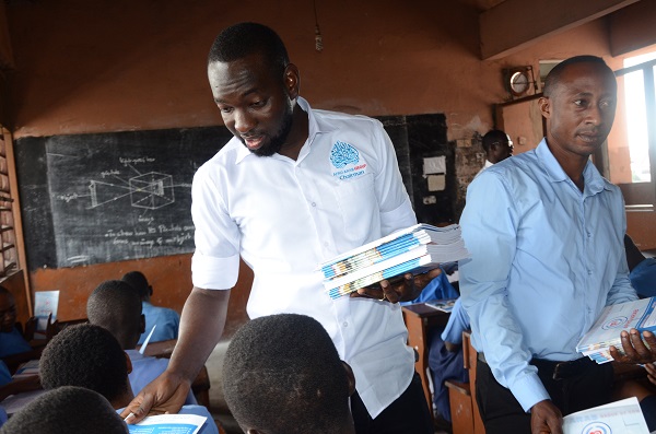 The Chief Executive Officer (CEO) of Afro-Arab Group of Companies, Alhaji Abdul Salamu Amadou handing out books to some students during the donation.