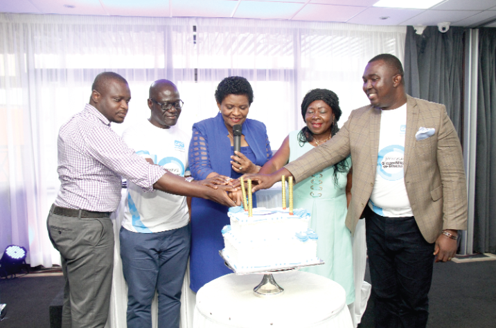 Mr Sakyi- Hyde (right) being assisted by other executives and customers to cut the anniversary cake