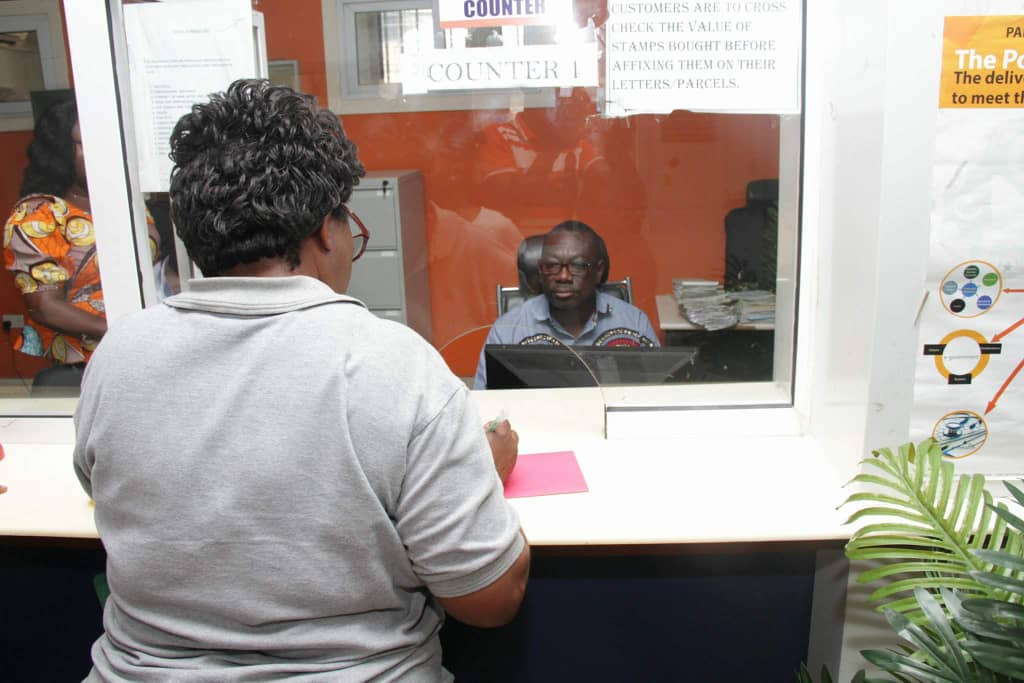 The Managing Director of Ghana Post, Mr James Kwofie, behind a counter serving a customer