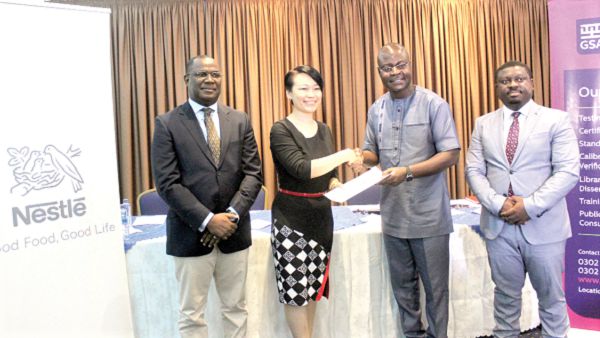  Prof. Alex Dodoo (2nd right) exchanging the agreement with Ms Philomena Tan (2nd left) after the signing. Those with them are officials from the two institutions 