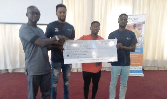 Mr Daniel Amoh (left), the Regional Coordinator, presenting a dummy cheque to three of the beneficiaries