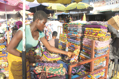 A trader arranging her African print fabrics.