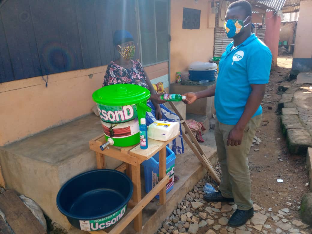 Mr Richard Quayson (right), Research and Publicity Officer at UCSOND presents sanitation items to a person with disability to aid COVID-19 fight  