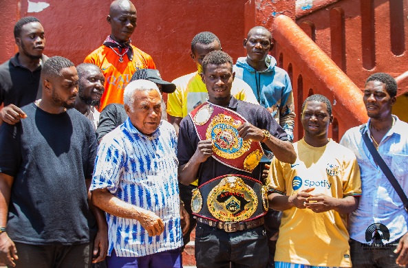 Faisal Abubakar displays his two belts after receiving the new crown from Samir Captan (2nd from left) while the boxer's manager and supporters join them 