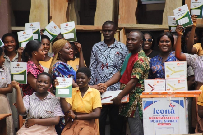 Adwoa Asantewaa(standing 3rd left), presenting the items to Reverend Prince Asamoah Kyei(3rd right), in the presence of some teachers and pupils of the Ahwiaa M/ JHS at Ahwiaa in the Ashanti Region.