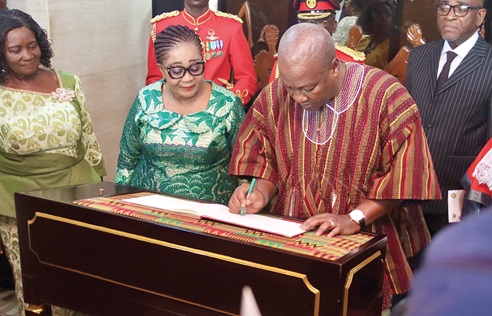 President John Dramani Mahama (right) signing the special visitors album. Looking on are Prof. Naana Jane Opoku-Agyemang (left), Vice-President, and Lordina Mahama (middle), First Lady