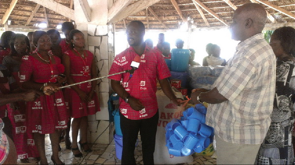 Mr Asamoah-Asante presenting the items to Rev. Lamina while other employees of Brisk credit look on.